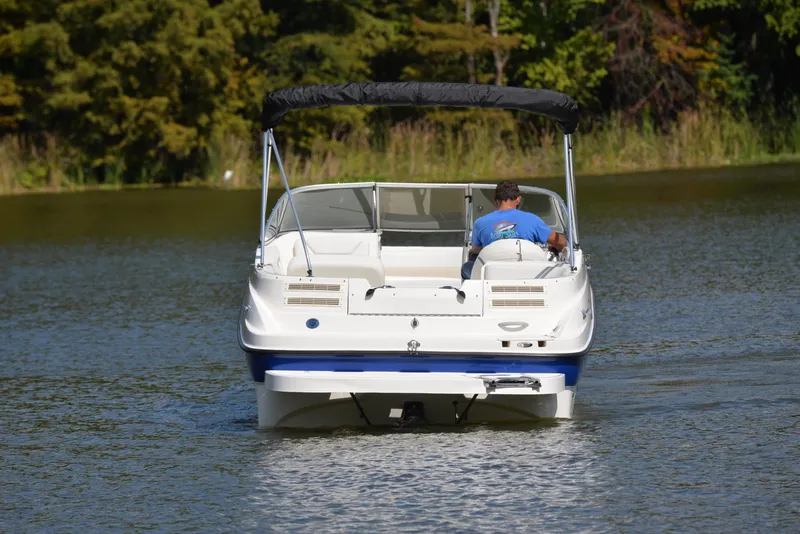 Slide: The Image of 2006 Bayliner 249 SD boat cruising on a calm lake with lush greenery. - 8