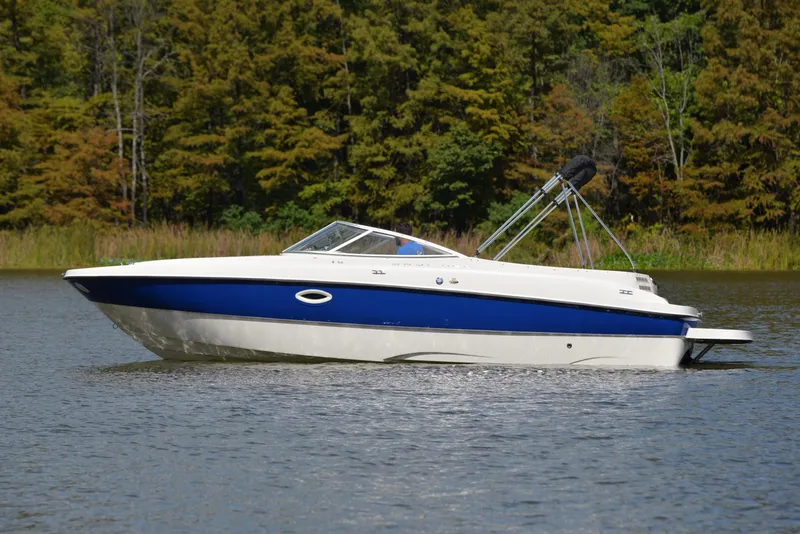 Slide: The Image of 2006 Bayliner 249 SD boat on a calm lake with forested background. - 9