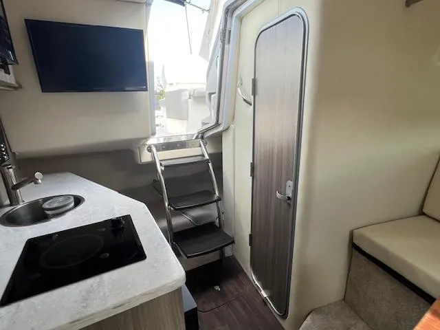Slide: The Image of Interior of 2019 Regal 26 Express boat with kitchenette, TV, and stairs. - 14