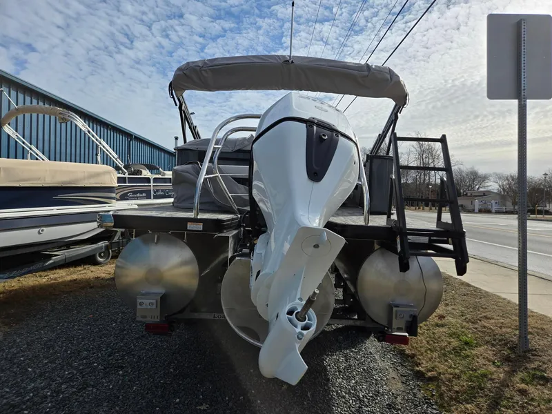 Slide: The Image of 2025 Godfrey Sweetwater 2286 C pontoon boat with outboard motor, parked on gravel. - 3