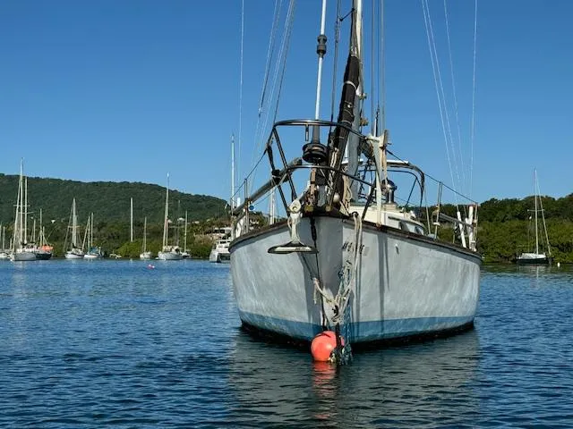 Slide: The Image of 1980 Cape Dory 36 sailboat anchored in a scenic harbor with other boats. - 2
