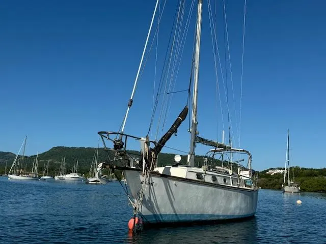 Slide: The Image of 1980 Cape Dory 36 sailboat anchored in a scenic bay with clear blue skies. - 3