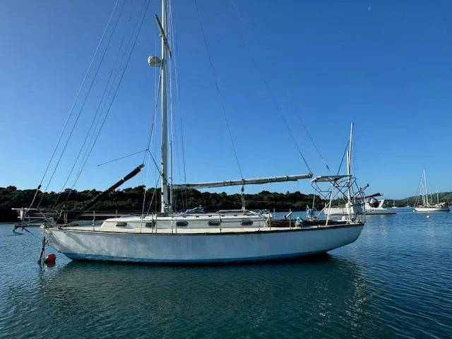Slide: The Image of 1980 Cape Dory 36 sailboat anchored on calm water under clear blue sky. - 5