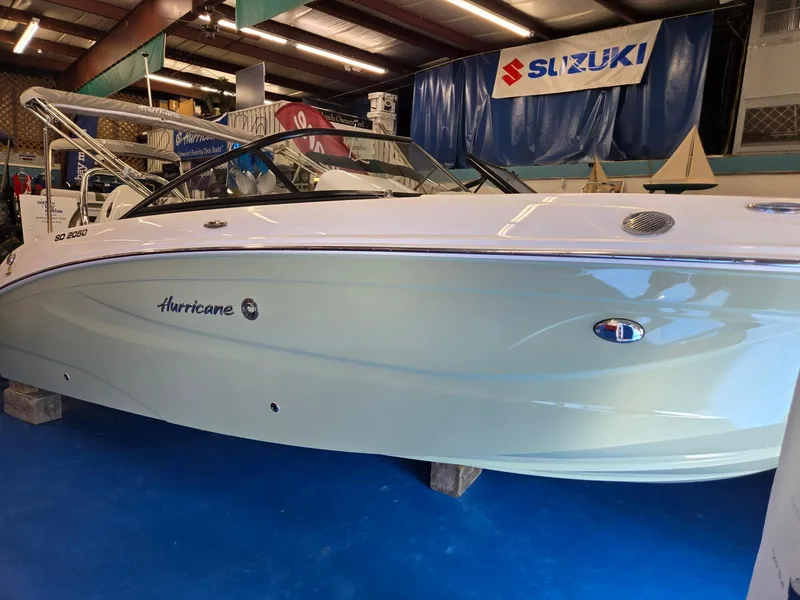 Slide: The Image of 2025 Hurricane SunDeck 2050 OB boat displayed indoors with Suzuki banner. - 0