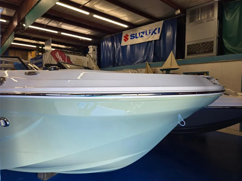 Slide: The Image of 2025 Hurricane SunDeck 2050 OB boat displayed indoors, under Suzuki banner. - 1