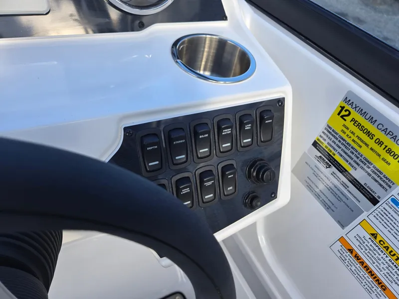 Slide: The Image of Control panel of 2025 Hurricane SunDeck 235 OB boat with capacity label and cup holder. - 17