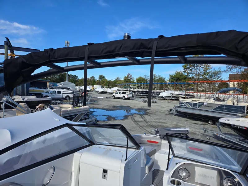 Slide: The Image of 2025 Hurricane SunDeck 235 OB boat in marina, surrounded by parked vehicles and other boats. - 34