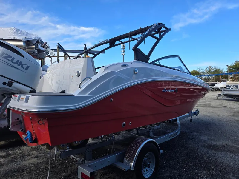 Slide: The Image of 2025 Hurricane SunDeck 235 OB boat, red and white, on a trailer in a marina. - 4