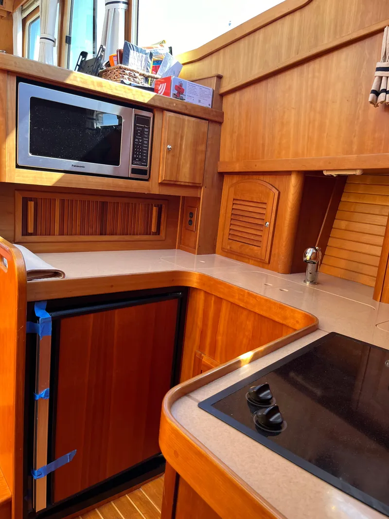 Slide: The Image of 2004 Sabre 36 Sedan yacht kitchen with microwave, stove, and wooden cabinetry. - 25