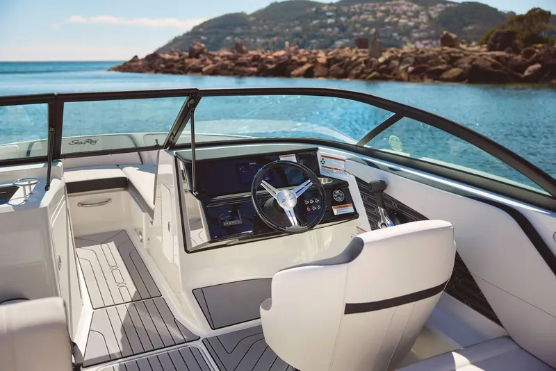 Slide: The Image of 2024 Sea Ray 210SPX boat interior with steering wheel, overlooking scenic coastal view. - 7
