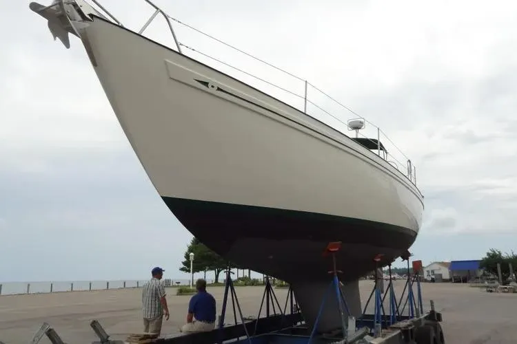 Slide: The Image of 1978 Rival 41C sailboat on trailer, two people nearby, overcast sky. - 26