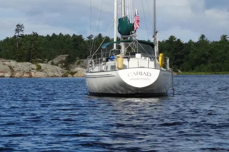 Slide: The Image of Sailboat "Cariad" on water, Rival 41C model, 1978, with forested shoreline background. - 3