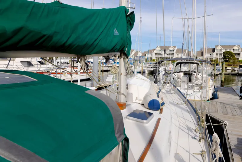 Slide: The Image of 1978 Rival 41C sailboat docked at marina with green covers and nearby boats. - 36