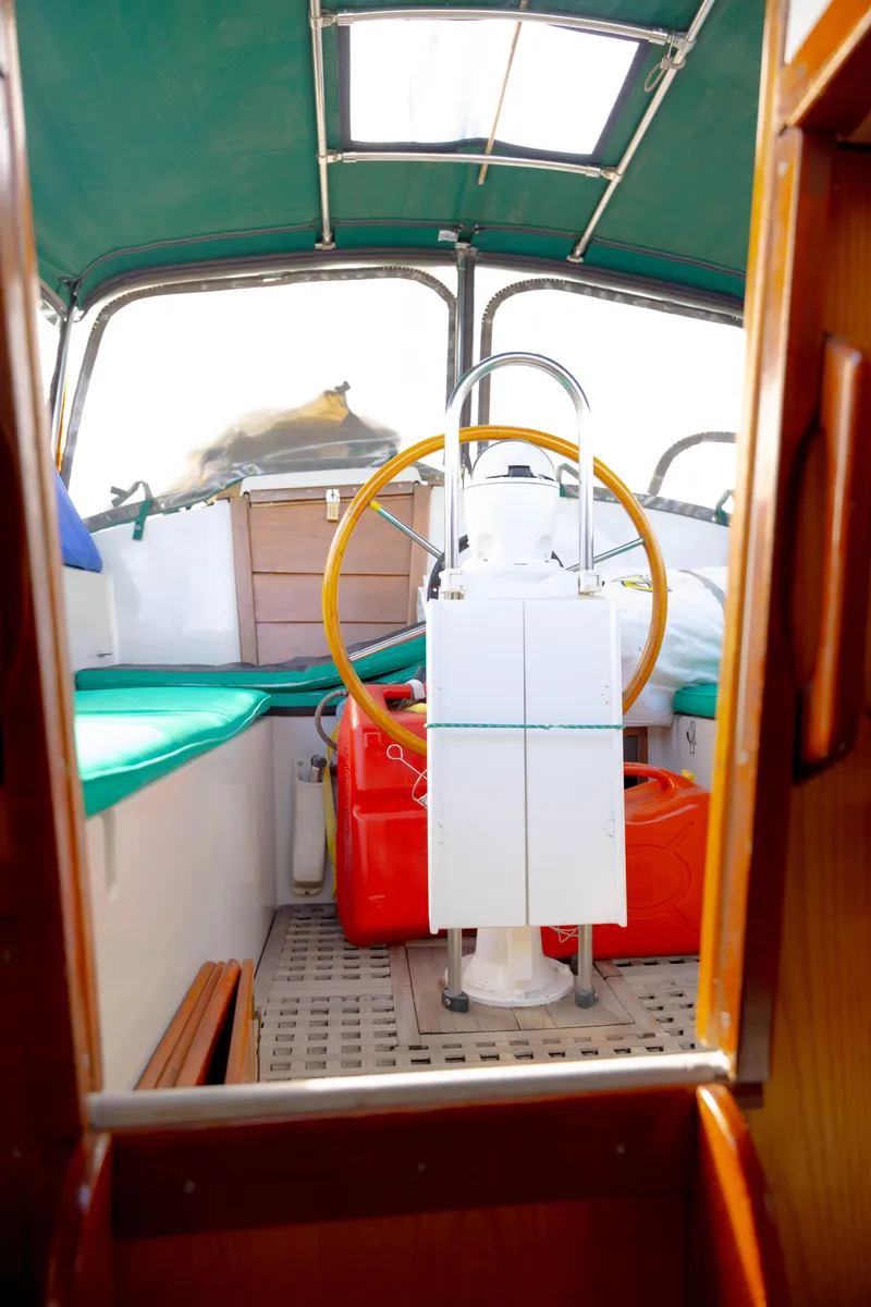 Slide: The Image of Interior view of a 1978 Rival 41C sailboat cockpit with green canopy and wooden steering wheel. - 43
