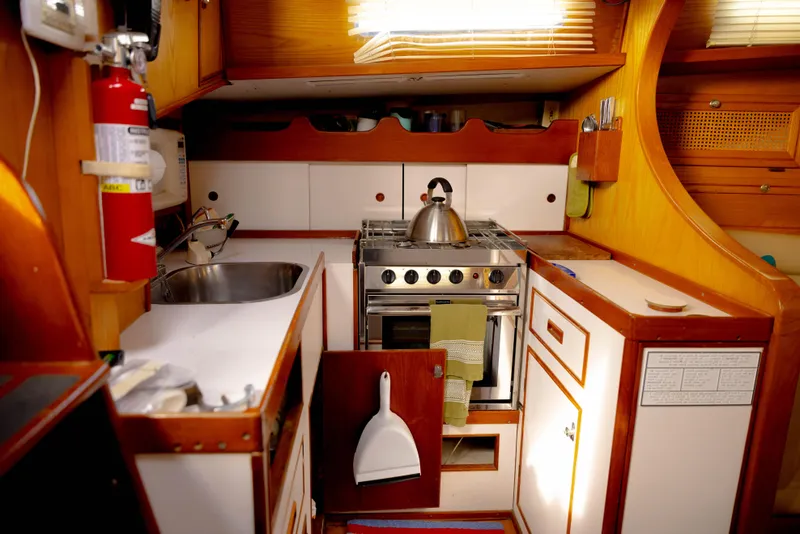 Slide: The Image of 1978 Rival 41C yacht kitchen with stove, sink, and wooden cabinetry. - 44