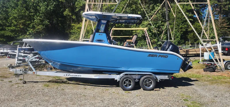 The Image of 2025 Sea Pro 242 DLX boat on trailer, blue hull, parked outdoors. - 1