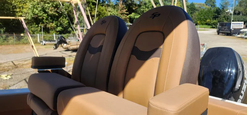 Slide: The Image of 2025 Sea Pro 242 DLX boat seats, tan and black, in outdoor setting. - 7