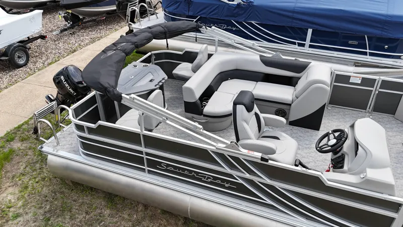 Slide: The Image of 2025 South Bay 220 F pontoon boat with seating and steering console, docked on grass. - 12
