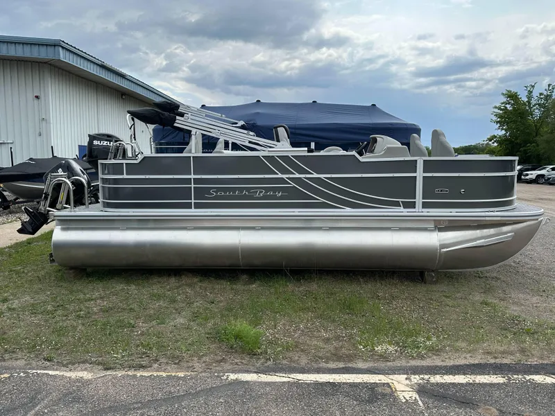 Slide: The Image of 2025 South Bay 220 F pontoon boat parked outdoors near a building. - 6