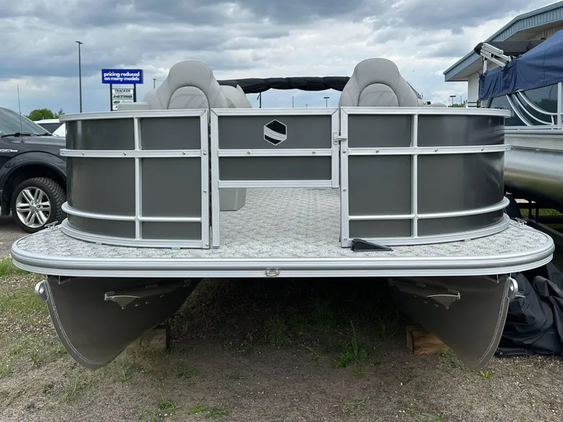 Slide: The Image of 2025 South Bay 220 F pontoon boat, gray exterior, parked on grass under cloudy sky. - 7