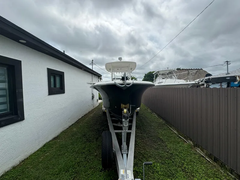 Slide: The Image of 2011 Sea Hunt Gamefish 29 boat on trailer beside house under cloudy sky. - 2