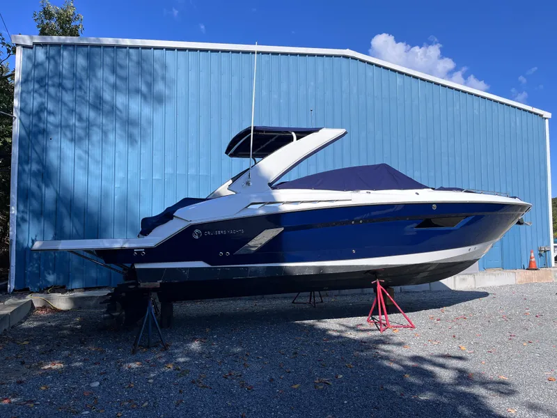 Slide: The Image of 2021 Cruisers Yachts 338 CX IO boat on stands, blue exterior, parked outdoors. - 1