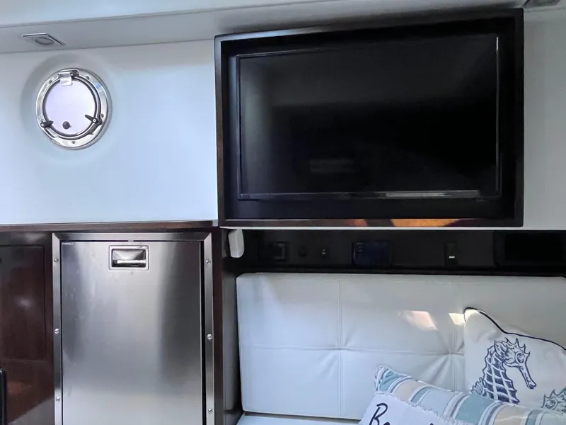Slide: The Image of Interior of 2021 Cruisers Yachts 338 CX IO with TV, porthole, and seating area. - 13