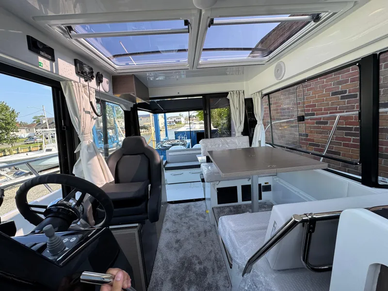 Slide: The Image of Interior of 2025 Jeanneau NC 895 Series 2 boat, featuring modern seating and steering area. - 11