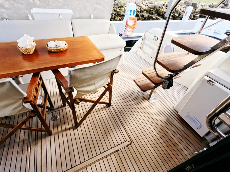 Slide: The Image of Prestige 460 yacht deck with wooden table, chairs, and stairs, 2020 model. - 18