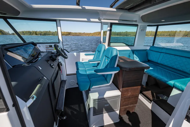 Slide: The Image of 2024 Axopar 37 XC BRABUS interior with blue seating and wet bar on a lake. - 9