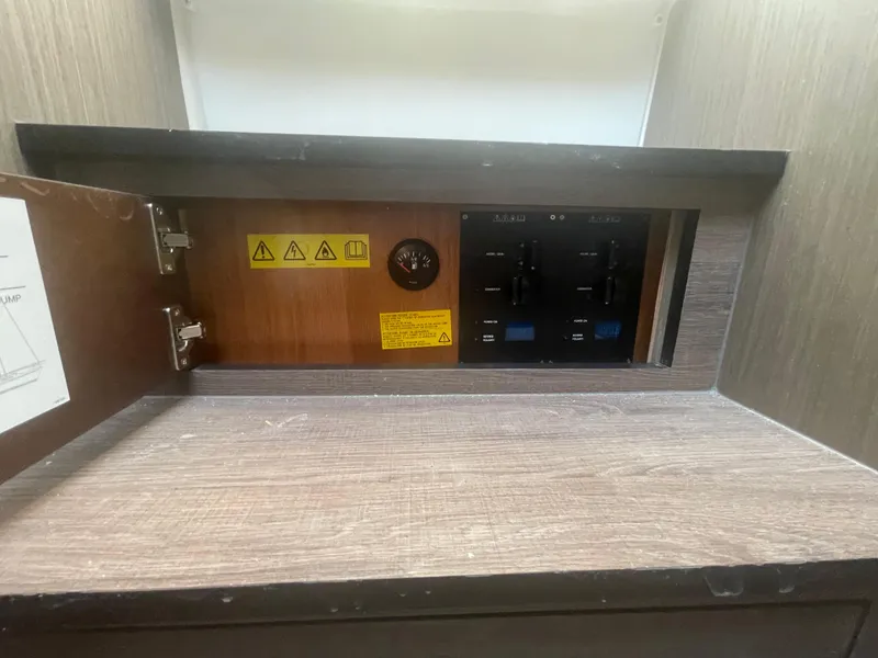 Slide: The Image of Electrical panel inside 2024 Beneteau Gran Turismo 32 yacht, featuring control switches and warning labels. - 14