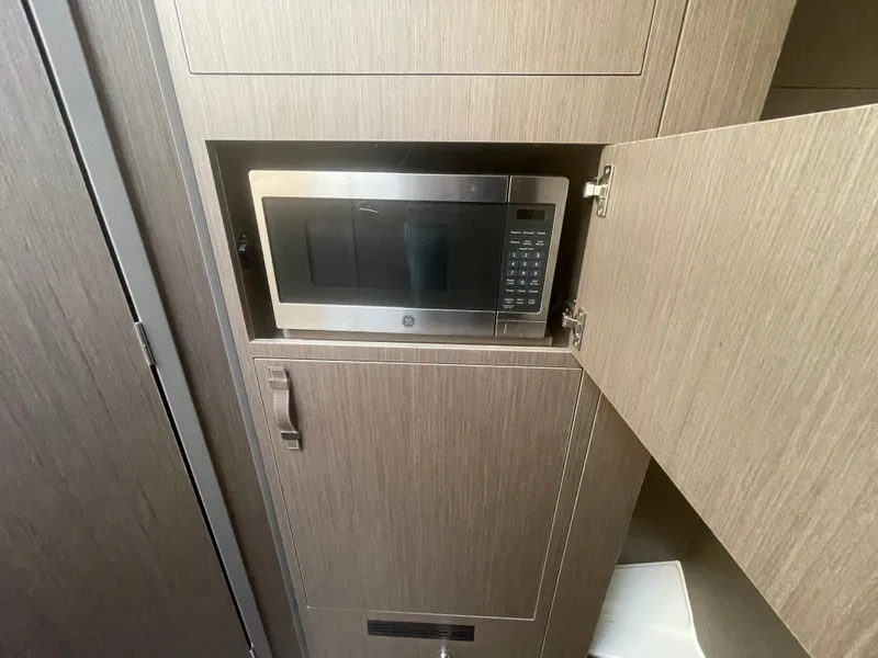 Slide: The Image of 2024 Beneteau Gran Turismo 32 interior with built-in microwave in wooden cabinetry. - 28