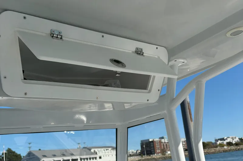 Slide: The Image of Open storage compartment on 2021 Release 240RX boat, with coastal background. - 8