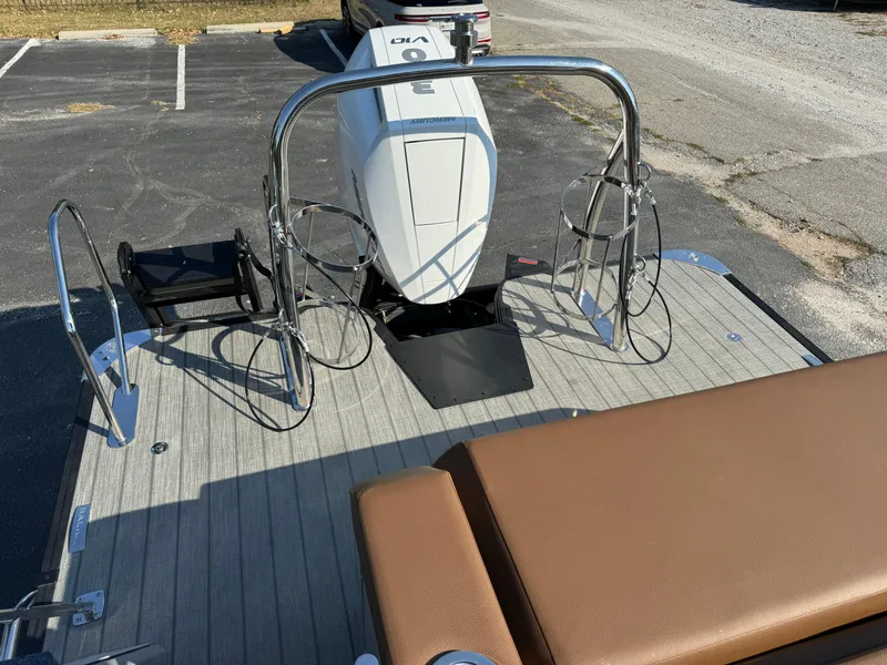 Slide: The Image of 2025 Balise Helix 24L boat deck with seating and motor, parked on asphalt. - 22