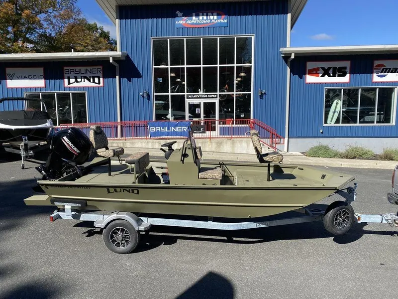 The Image of 2025 Lund 1870 Predator Z1870C Center Console boat on trailer, parked outside dealership. - 1
