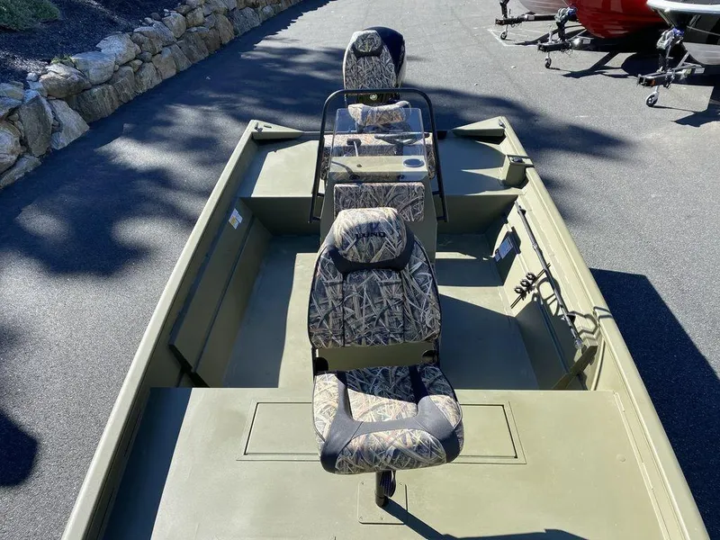 Slide: The Image of 2025 Lund 1870 Predator Z1870C Center Console boat with camo seats, parked on pavement. - 10