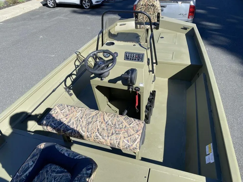 Slide: The Image of 2025 Lund 1870 Predator Z1870C Center Console boat with camo seats, parked outdoors. - 7