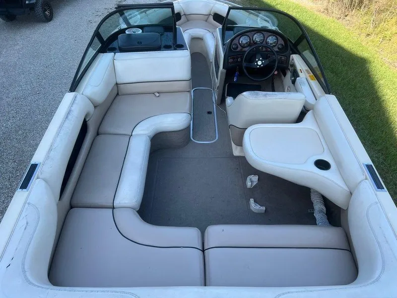 Slide: The Image of 1999 Malibu Sunsetter VLX boat interior with beige seating and steering console. - 2