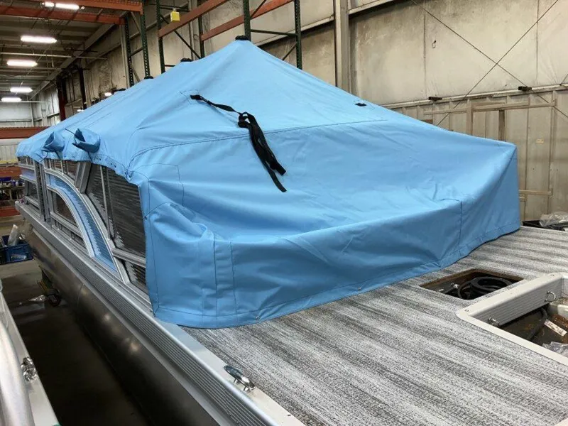 Slide: The Image of 2025 Bennington 22SLJ pontoon boat with blue cover in a warehouse. - 12