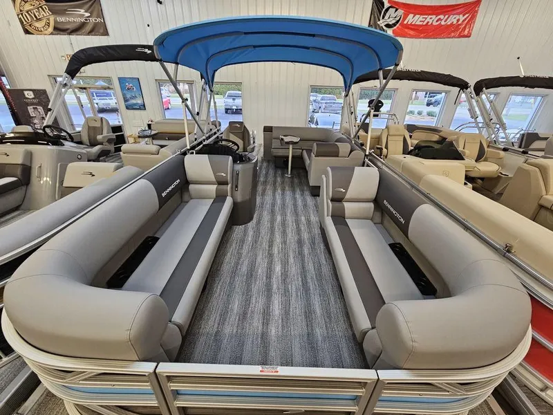 Slide: The Image of 2025 Bennington 22SLJ pontoon boat with spacious seating and blue canopy in showroom. - 2