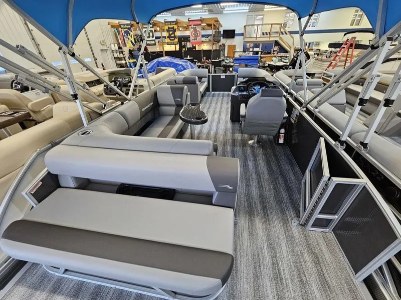 Slide: The Image of 2025 Bennington 22SLJ pontoon boat interior with gray seating and blue canopy. - 6