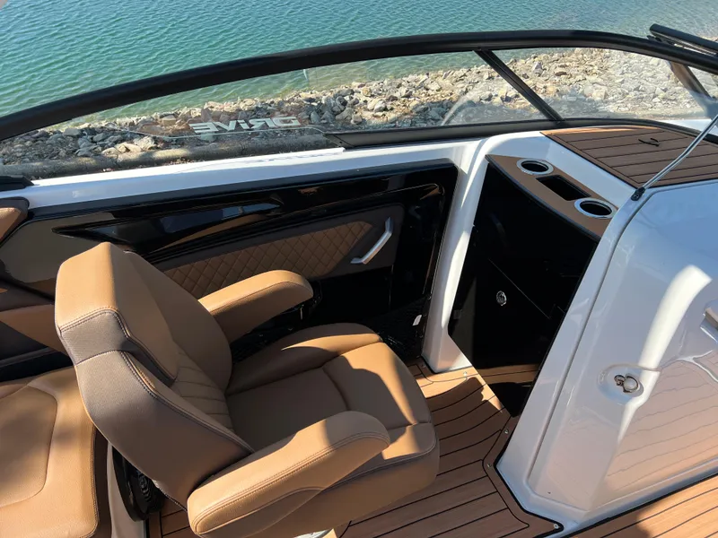 Slide: The Image of 2025 Yamaha Boats 252SD interior with tan seating and sleek design by the water. - 12