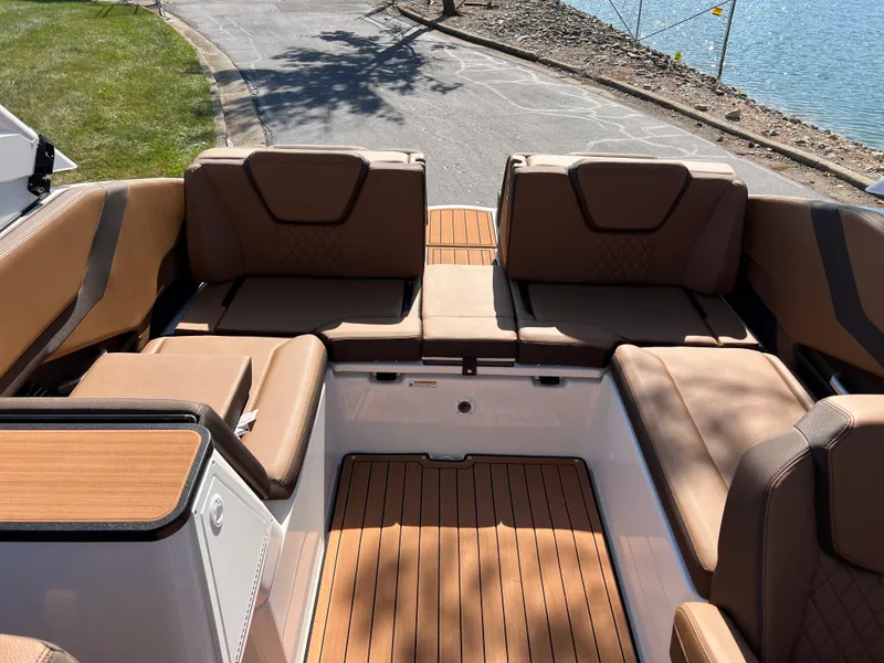 Slide: The Image of 2025 Yamaha Boats 252SD interior with luxurious seating and wood finish near a lake. - 27