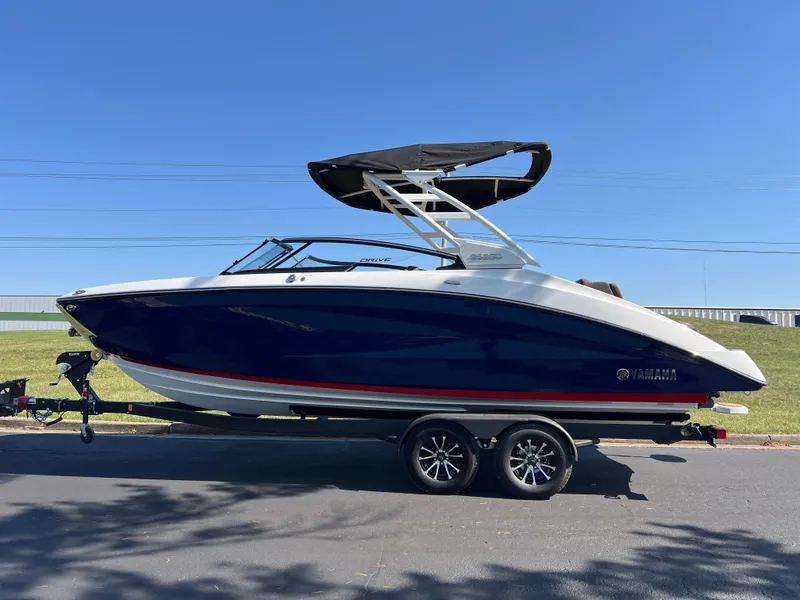 Slide: The Image of 2025 Yamaha Boats 252SD on trailer, sleek design, blue and white exterior, sunny day. - 5