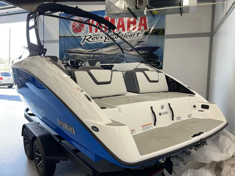 Slide: The Image of 2025 Yamaha AR250 boat in showroom, blue and white design, on trailer. - 3