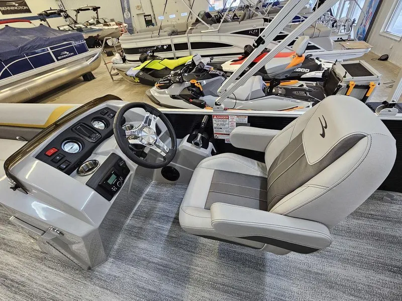 Slide: The Image of 2025 Bennington 22 SXL boat interior with steering wheel and captain's chair in showroom. - 10
