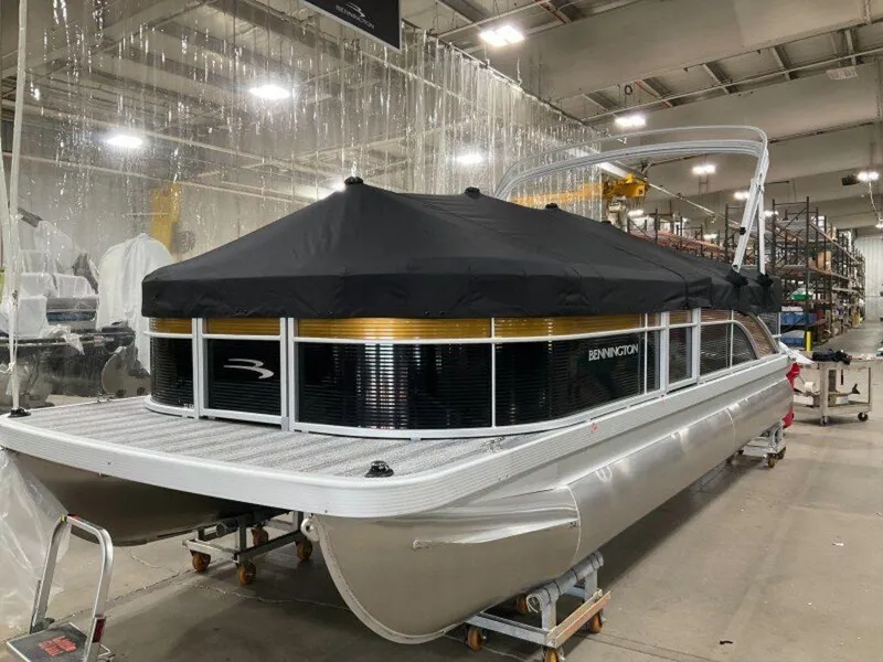 Slide: The Image of 2025 Bennington 22 SXL pontoon boat with black cover in a warehouse setting. - 12