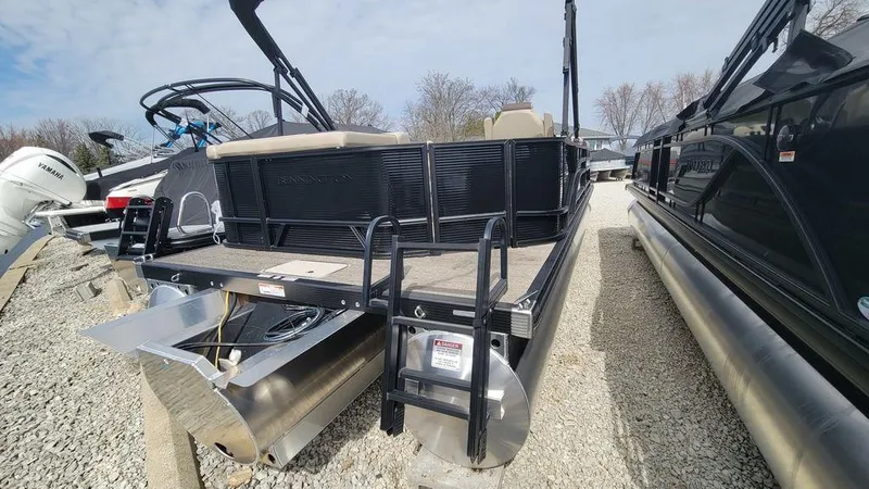 Slide: The Image of 2025 Bennington 23 SL pontoon boat, rear view, parked on gravel lot. - 18