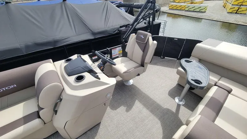 Slide: The Image of 2025 Bennington 23 SL boat interior with helm, seating, and table on a sunny day. - 22