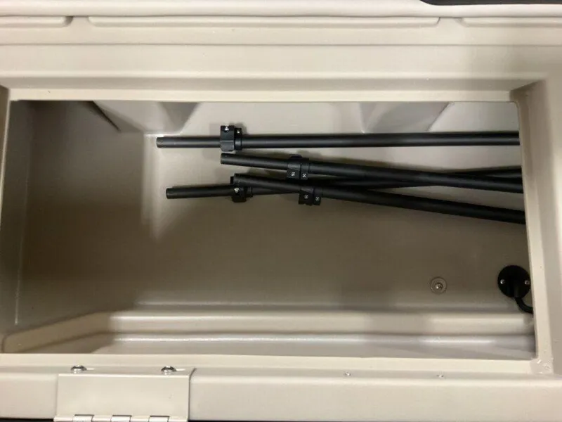 Slide: The Image of Storage compartment with black rods inside a 2025 Bennington 23 SL boat. - 24